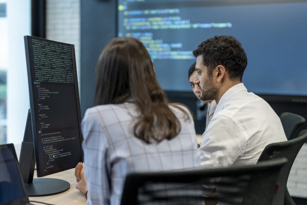 Software developers checking programming code on computer screen.