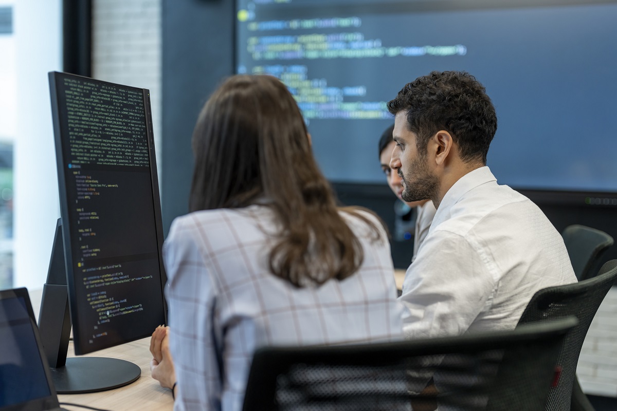 Software developers checking programming code on computer screen.