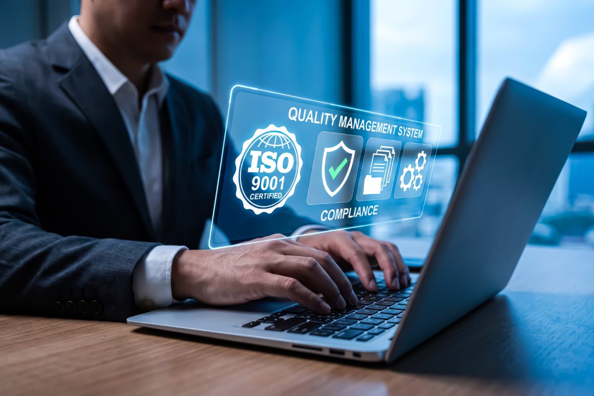 Businessman working on laptop with digital iso 9001 quality management system and compliance icons hologram